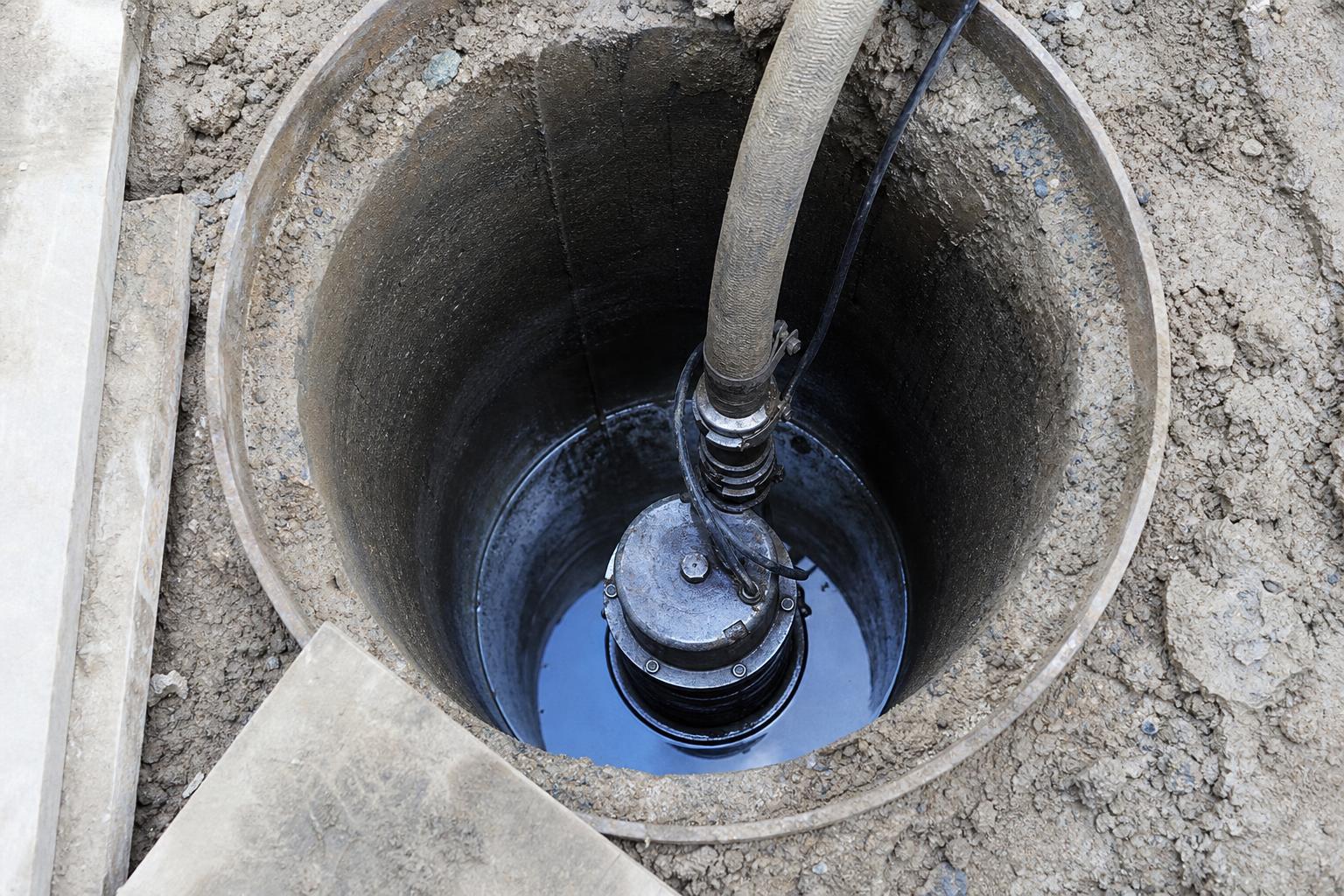 Погружной насос внутри водопонижающей скважины на строительной площадке