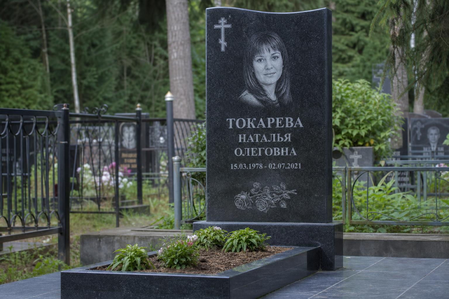 Гранитный памятник с видимыми частями: стелой, тумбой и цветником на кладбище
